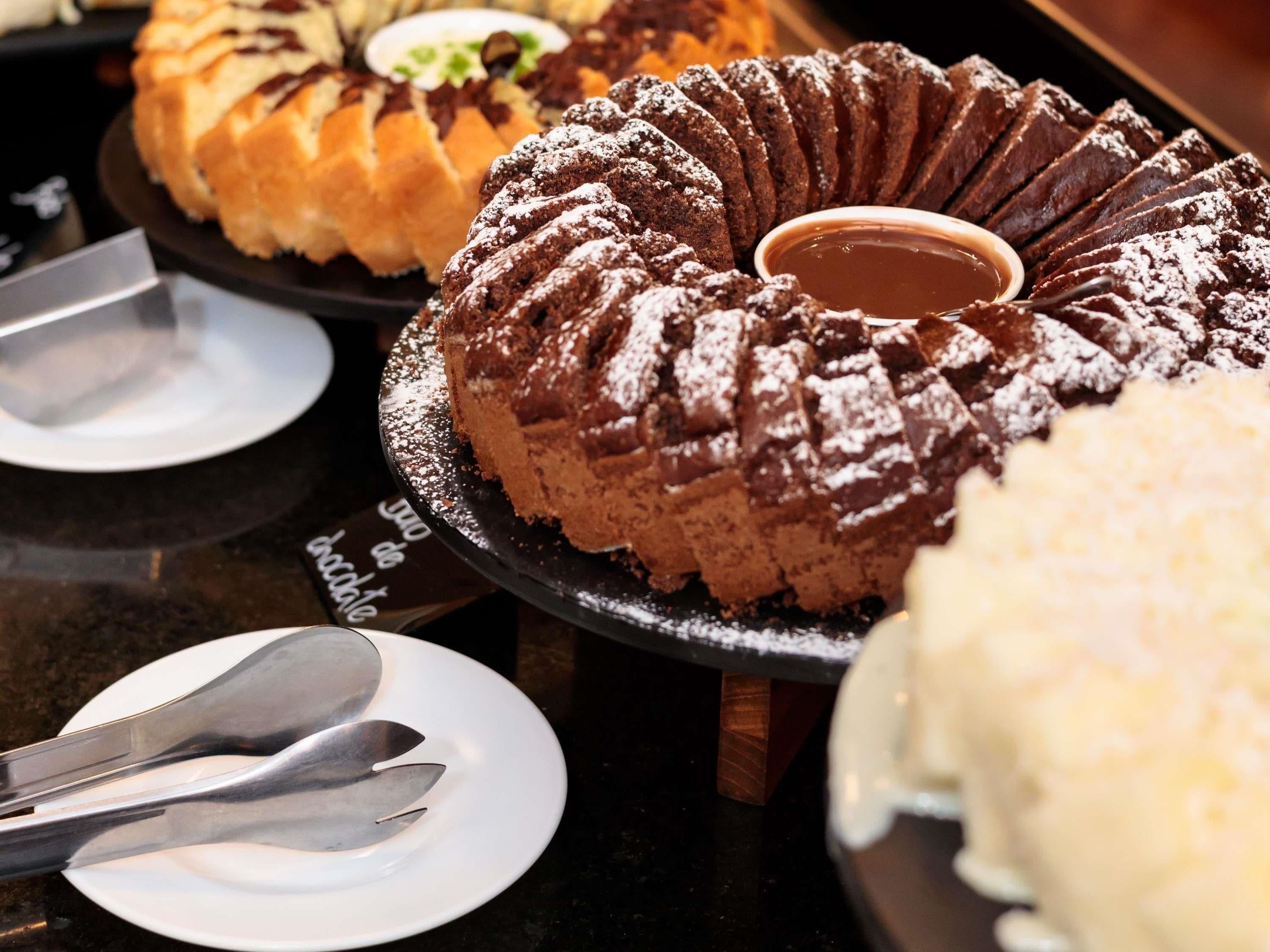 Un bufé de postres con diversos pasteles y un pastel bundt de chocolate con salsa de chocolate.