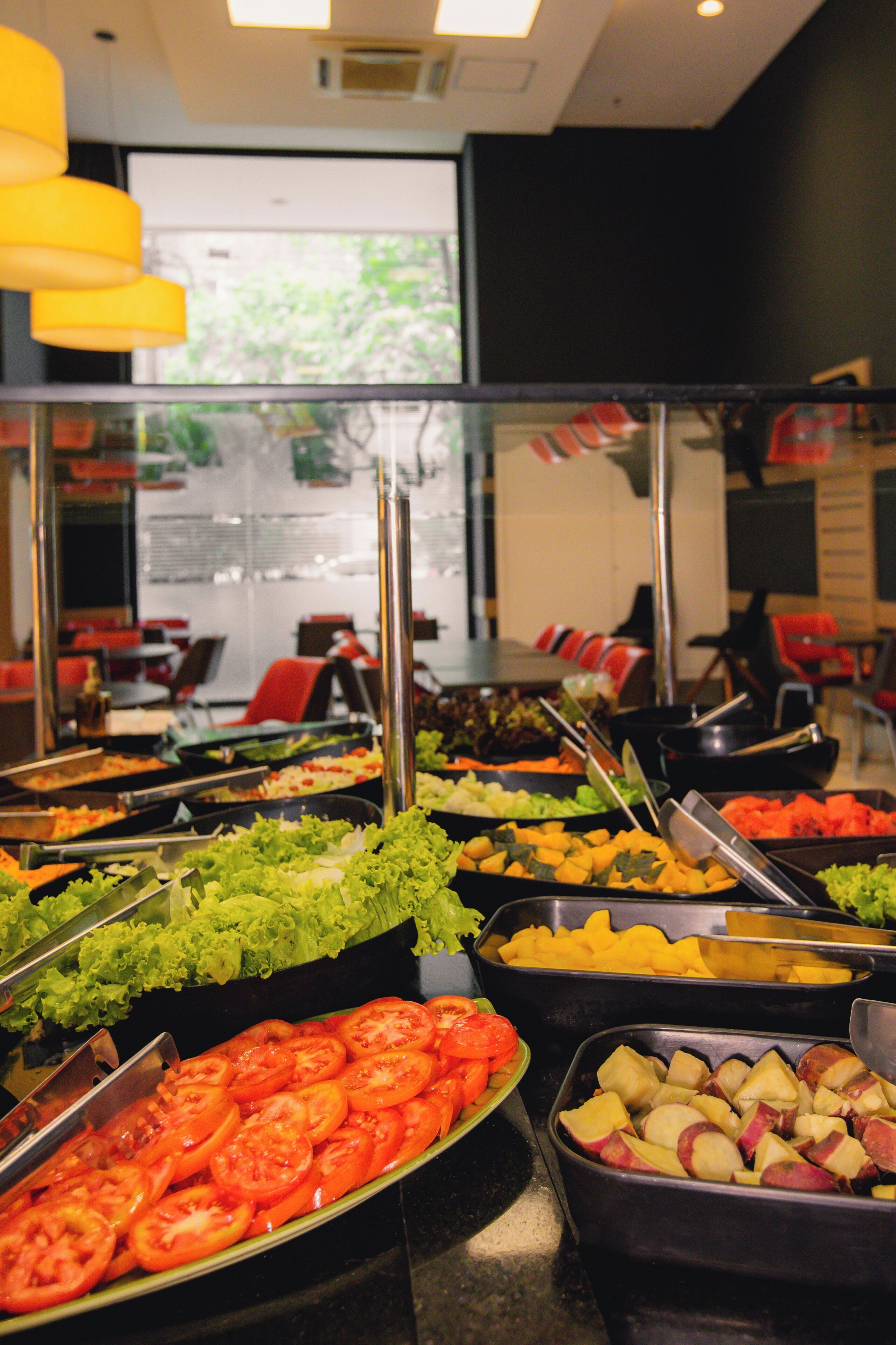 Buffet com diversas opções de comida, incluindo saladas, frutas e legumes.