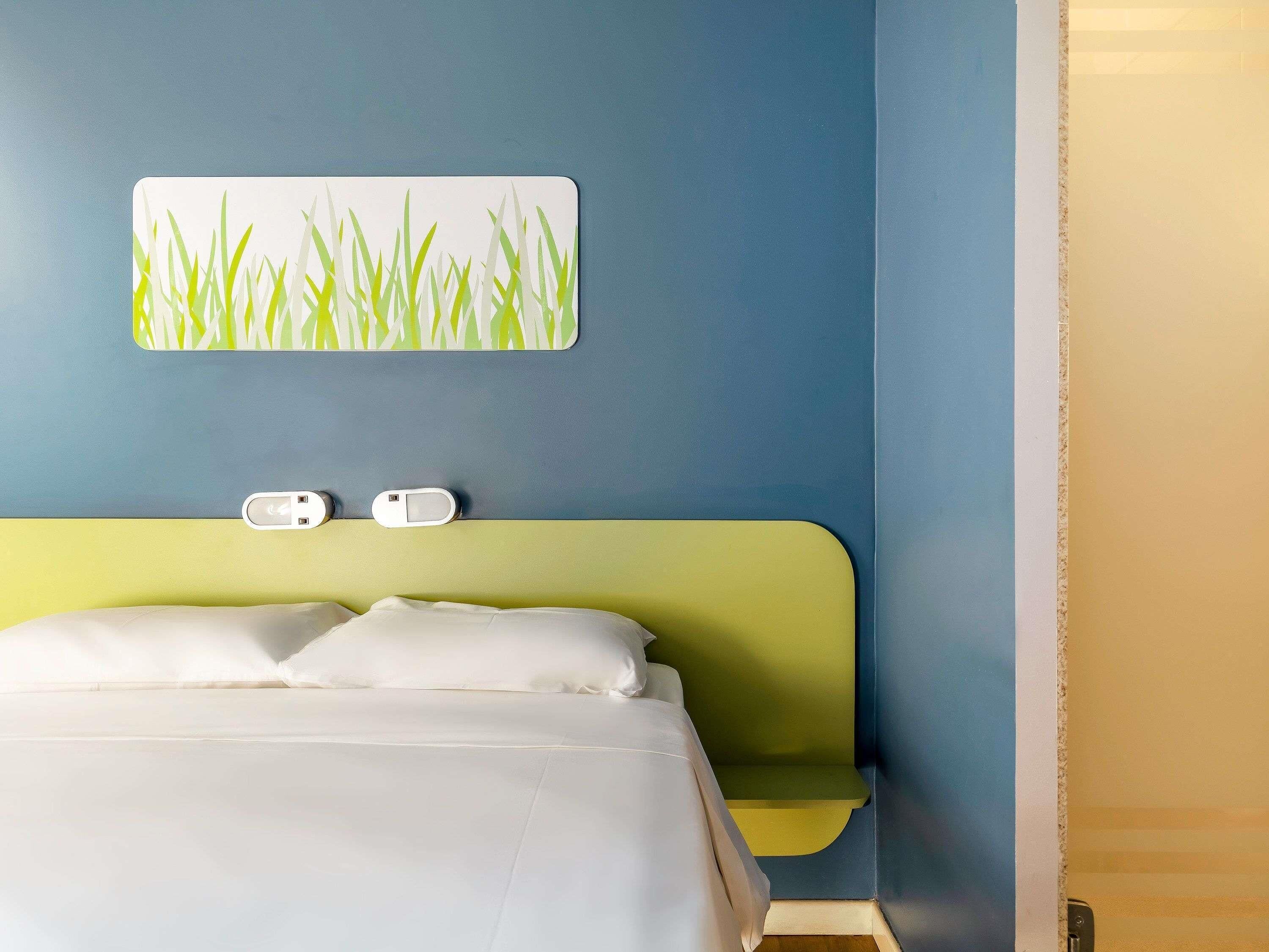 Ein Hotelzimmer mit einem Bett, einem Nachttisch und einer Wandladungestation.