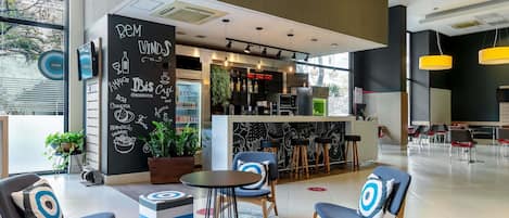En moderne café med et barområde, siddepladser med unikke puder og en tavlemenu.