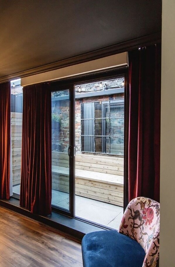 Una habitación con un amplio ventanal corredizo que da a una terraza de madera.