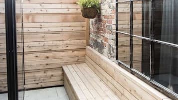 Una zona con bancos de madera, una pared de ladrillo y una ventana.