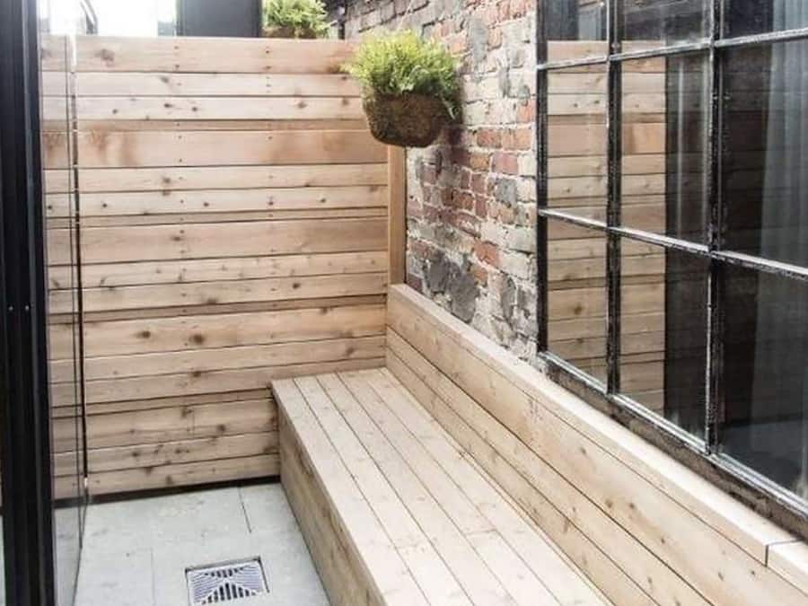 Una zona con bancos de madera, una pared de ladrillo y una ventana.