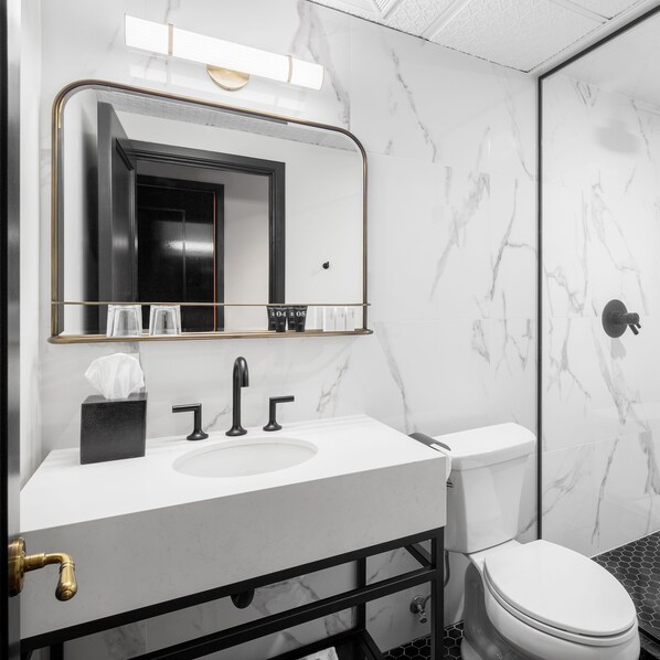A modern bathroom with a marble sink, a black toilet, and a large mirror.