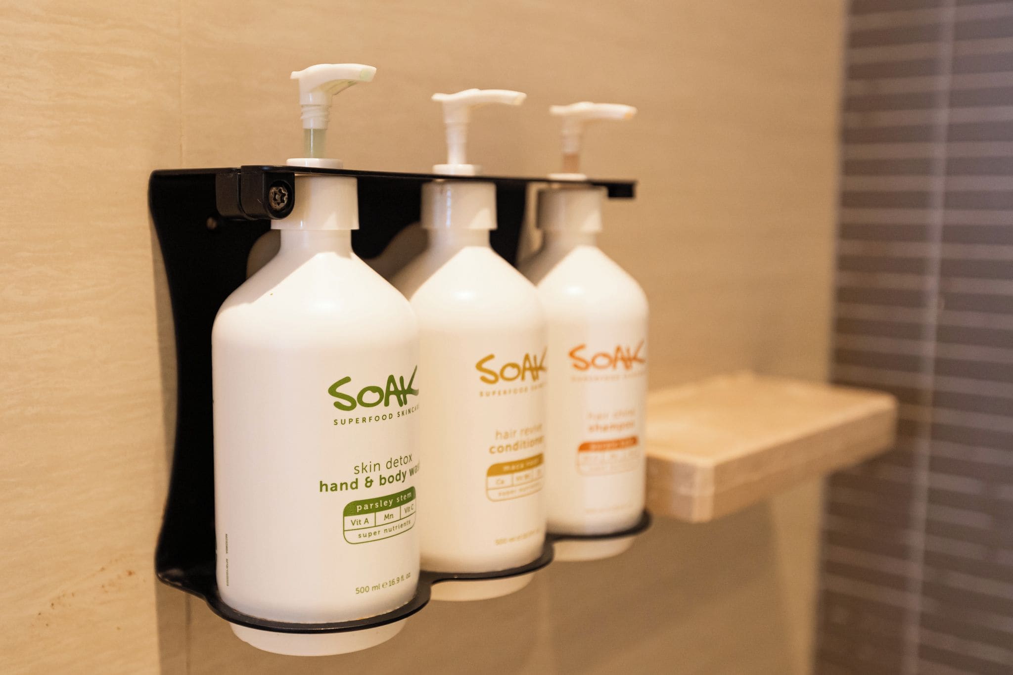 Three bottles of Soak hand and body wash on a wall-mounted dispenser.