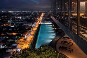 A high-rise hotel with a rooftop pool overlooking a cityscape at night. - Holiday Inn & Suites Rayong City Centre by IHG (Rayong)