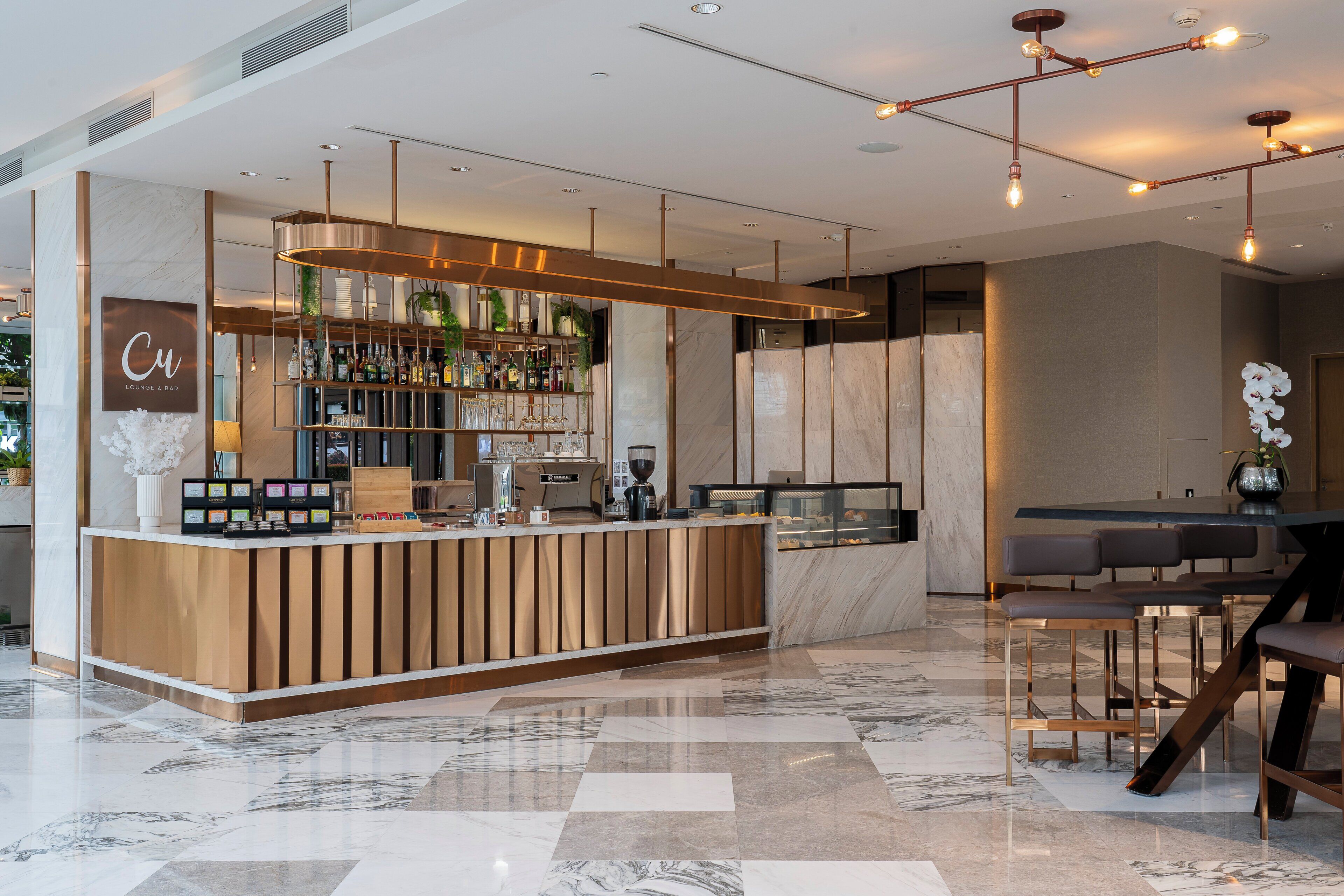 Un área de bar moderna con suelo de mármol, una máquina de café y una variedad de botellas.