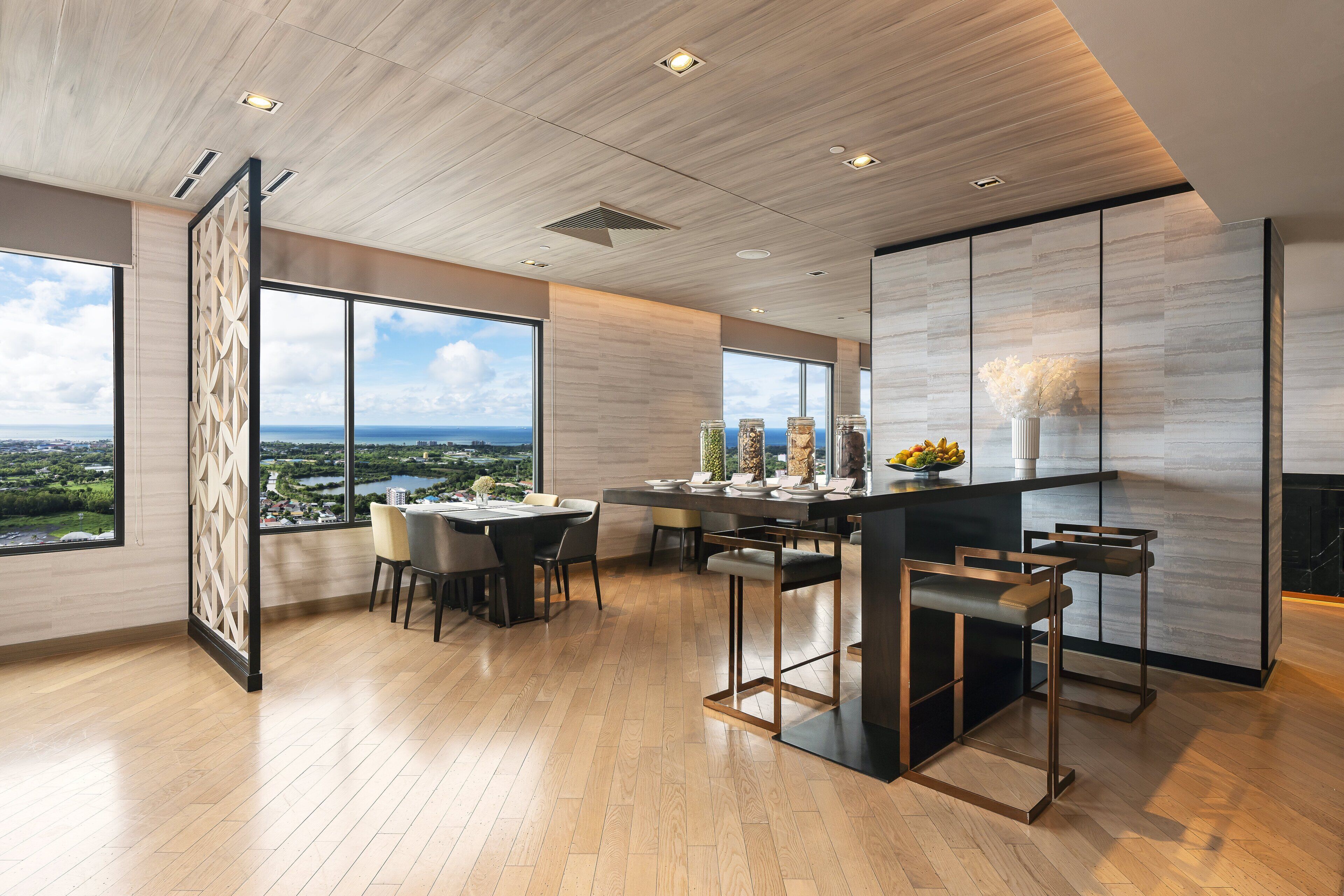 A modern kitchen with a dining area, large windows, and a view of the cityscape.