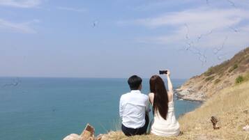 Una pareja sentada en un saliente rocoso con vista al litoral.