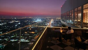 Una terrazza panoramica su un tetto con vista sulla città al crepuscolo.