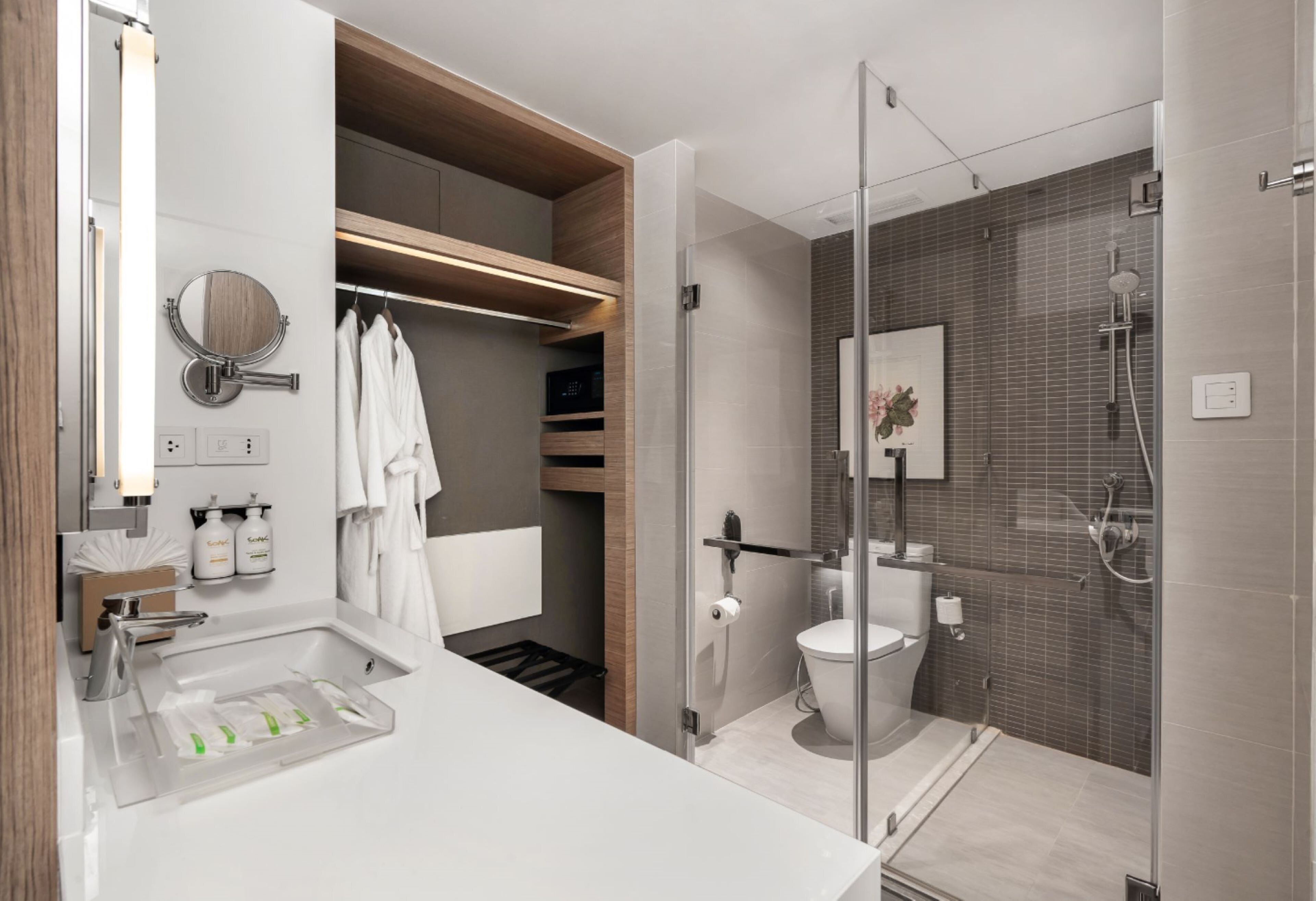 Une salle de bain moderne avec une douche à parois de verre, un lavabo blanc avec un porte-savon et un meuble-lavabo en bois.
