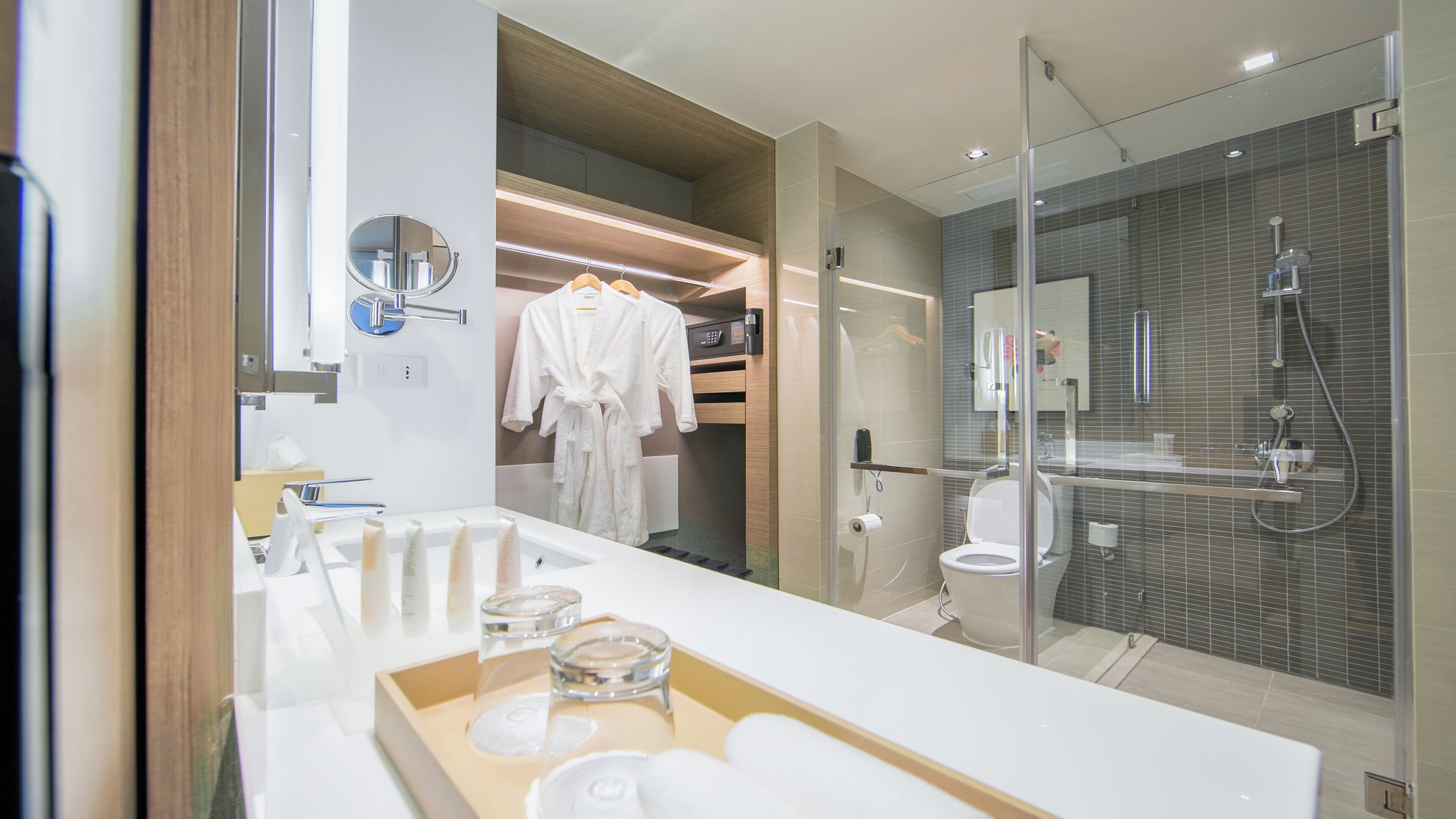 A modern bathroom with a glass-enclosed shower, a vanity with a mirror, and a towel rack.