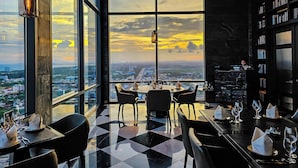 Un ristorante con vista panoramica sulla città, ampie finestre e un design d'interni moderno.