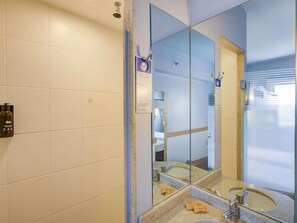 A bathroom with a large mirror, a shower, and a sink with soap. - ibis budget Rio de Janeiro Nova America (Rio de Janeiro)