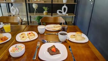 A dining table with breakfast items including cereal, pastries, and a slice of cake.