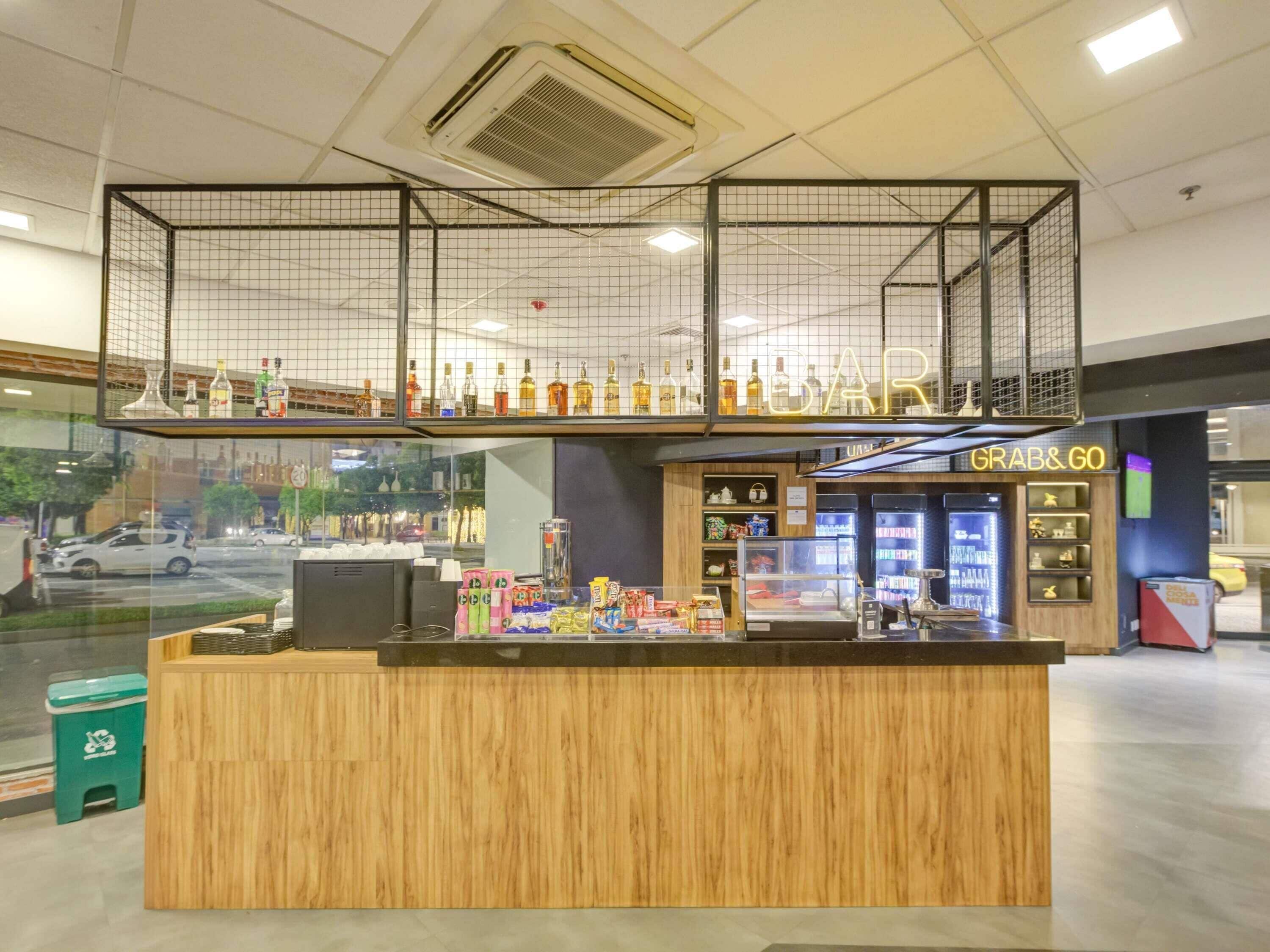 A bar area with a wooden counter and a display of various bottles.