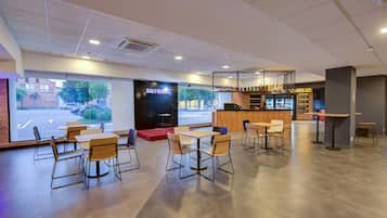 Un café moderno con un escenario para música en vivo, una zona de bar y una disposición de mesas y sillas.