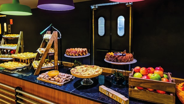 Een buffet met diverse etenswaren en een bord met de tekst 'BOMODIA'.
