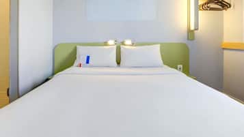 Una camera d'albergo con un letto, due comodini, una lampada a parete e un attaccapanni.