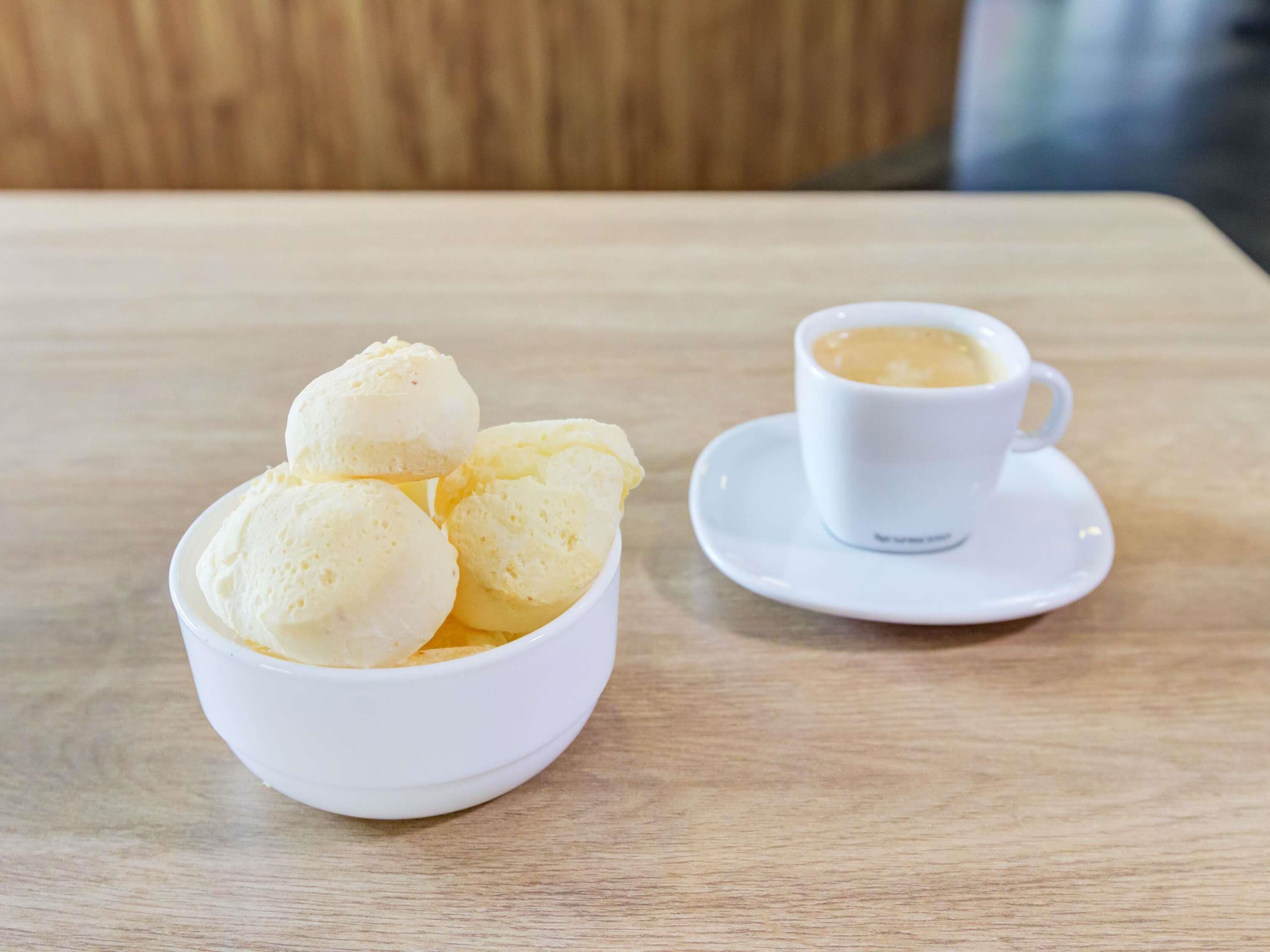 Een witte ijskom en een witte koffiekop op een houten tafel.