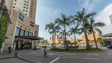 A hotel with a modern facade, palm trees, and a roundabout with cars.