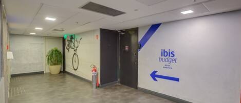 A hallway with a potted plant, a fire extinguisher, and a wall with 'ibis budget' signage.