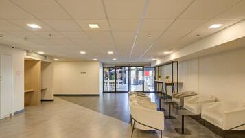 Un hall d’entrée spacieux comprenant un comptoir de réception, un espace détente et une entrée avec une porte vitrée.