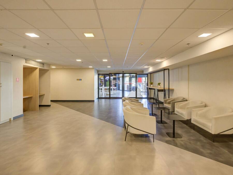 Un hall d’entrée spacieux comprenant un comptoir de réception, un espace détente et une entrée avec une porte vitrée.