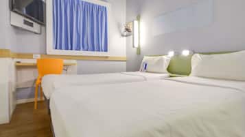 A hotel room with two beds, a desk, a chair, a TV, and a window with curtains.