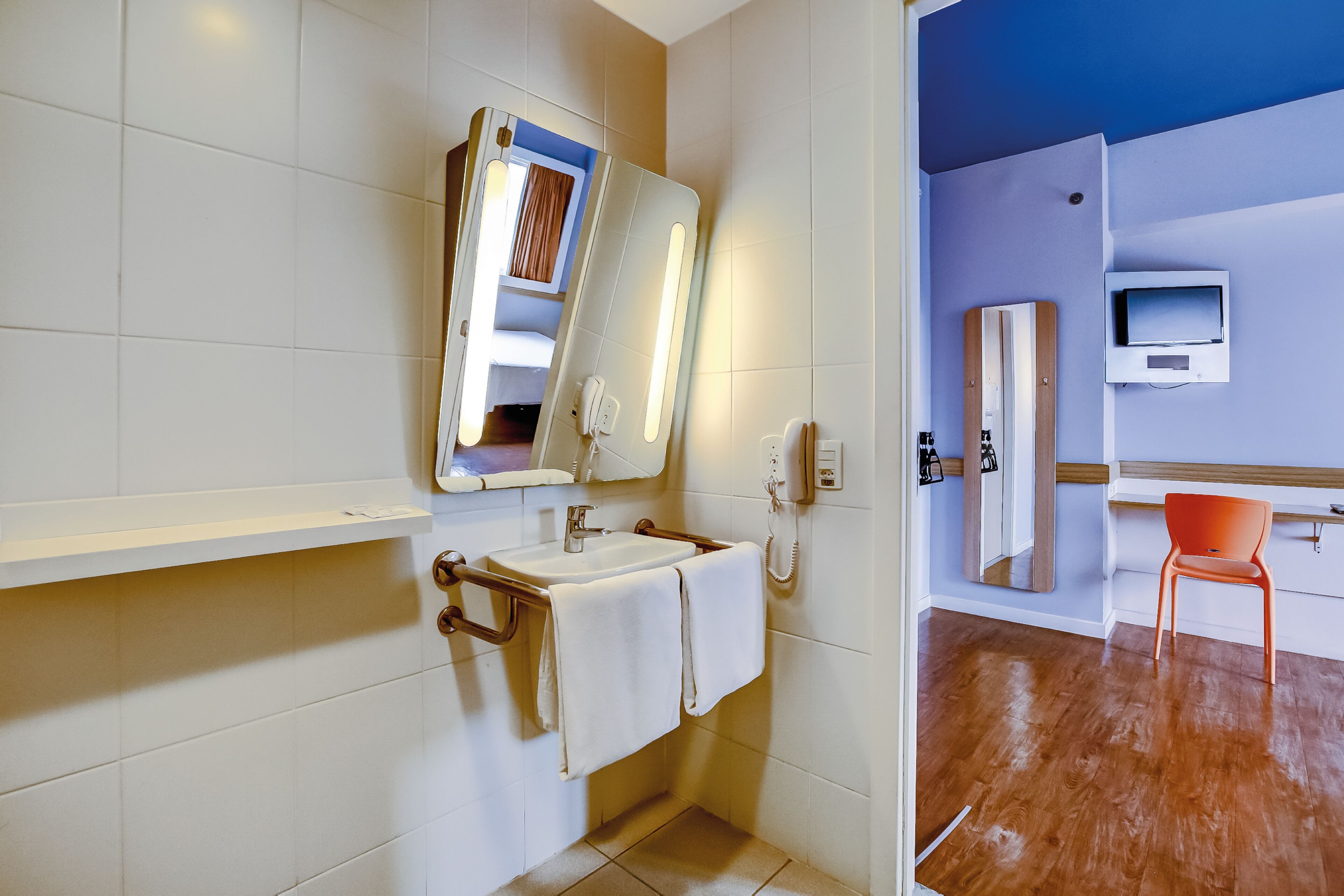 A bathroom with a sink, mirror, and towel rack.