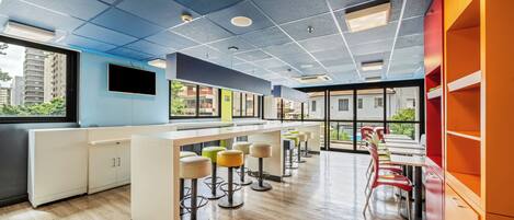 A modern kitchen with bar stools, a long counter, and a view of the city.