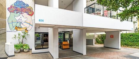 A modern building with a glass entrance, a number 826 sign, and a mural of a couple kissing.