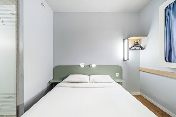 A single bed with a headboard, a nightstand, a wall-mounted shelf with a towel, and a window with curtains. - Slim Hotel São Paulo Frei Caneca (São Paulo)