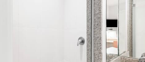 Un baño moderno con ducha, lavamanos de encimera de granito y espejo.