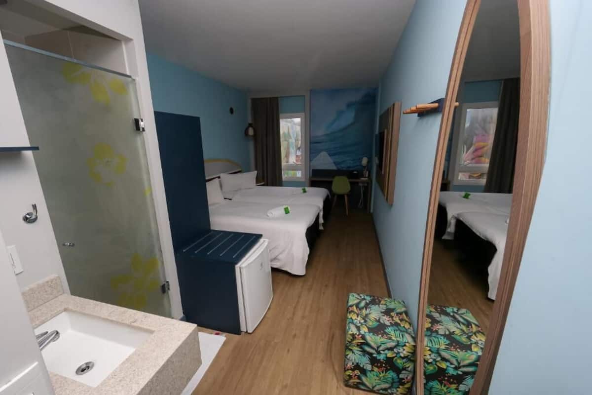 A hotel room with a shower, a bed, a desk, and a small seating area.