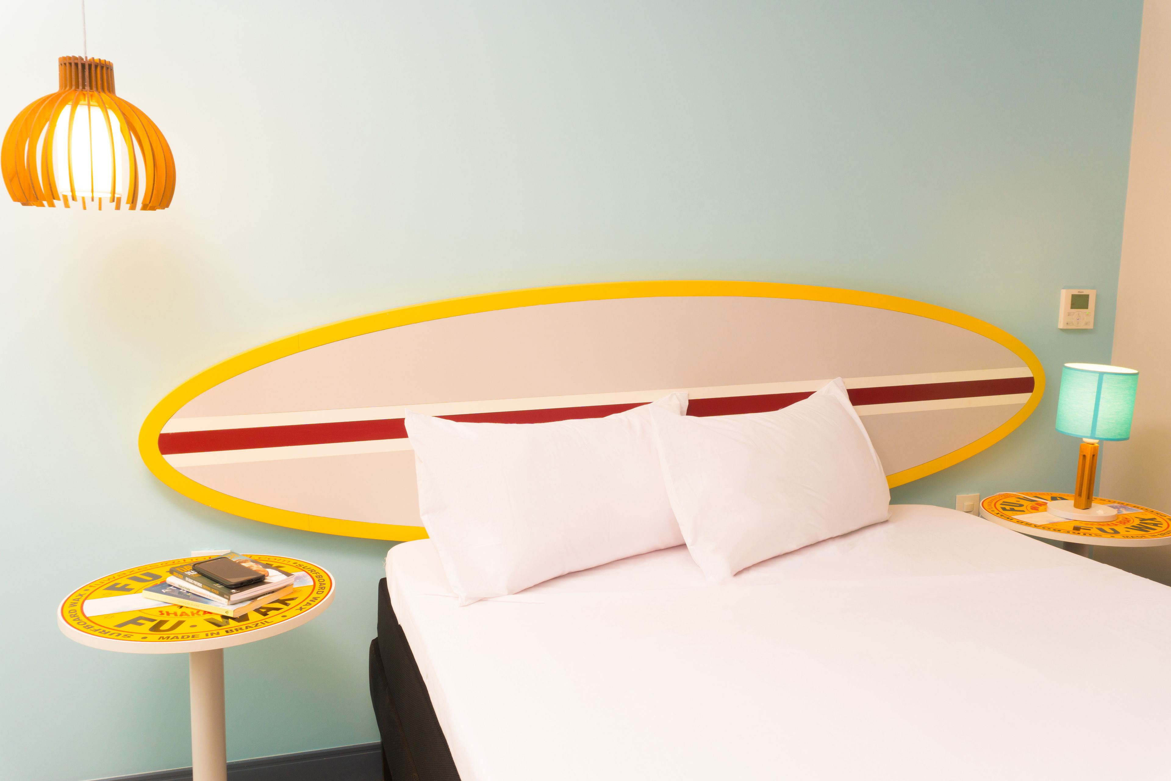 A hotel room with a bed, a round table with a lamp, and a wall-mounted light fixture.