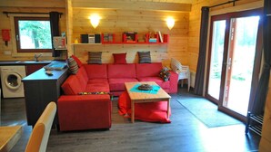 L’intérieur d’un chalet accueillant, avec un canapé rouge, une table en bois et un coin cuisine.