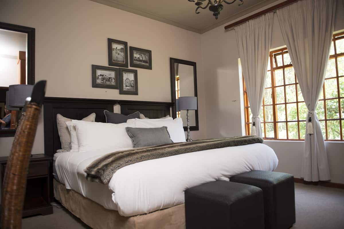 A neatly arranged bedroom with a large bed, bedside lamps, and a window with curtains.