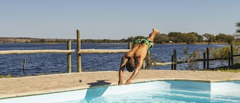 Una piscina al aire libre, sombrillas, sillones reclinables de piscina