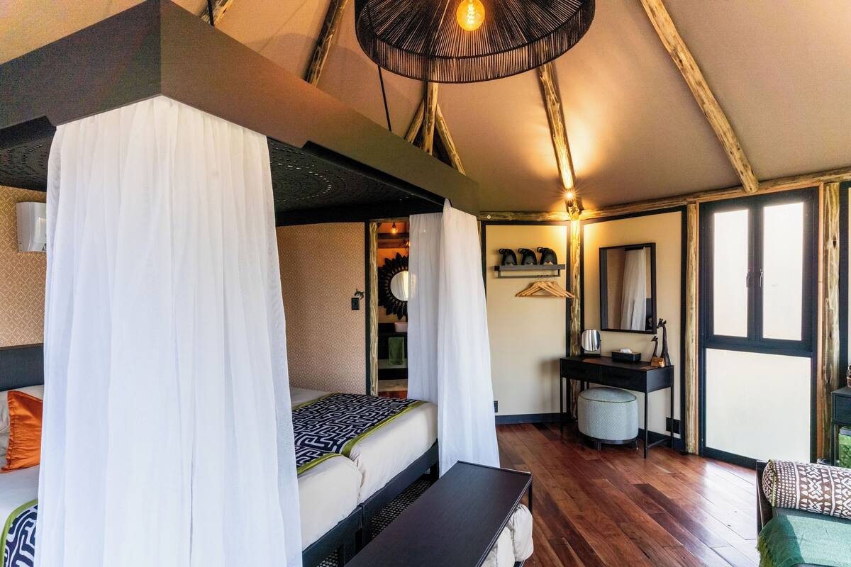 A bedroom with a canopy bed, a desk, a chair, and a hanging light fixture.