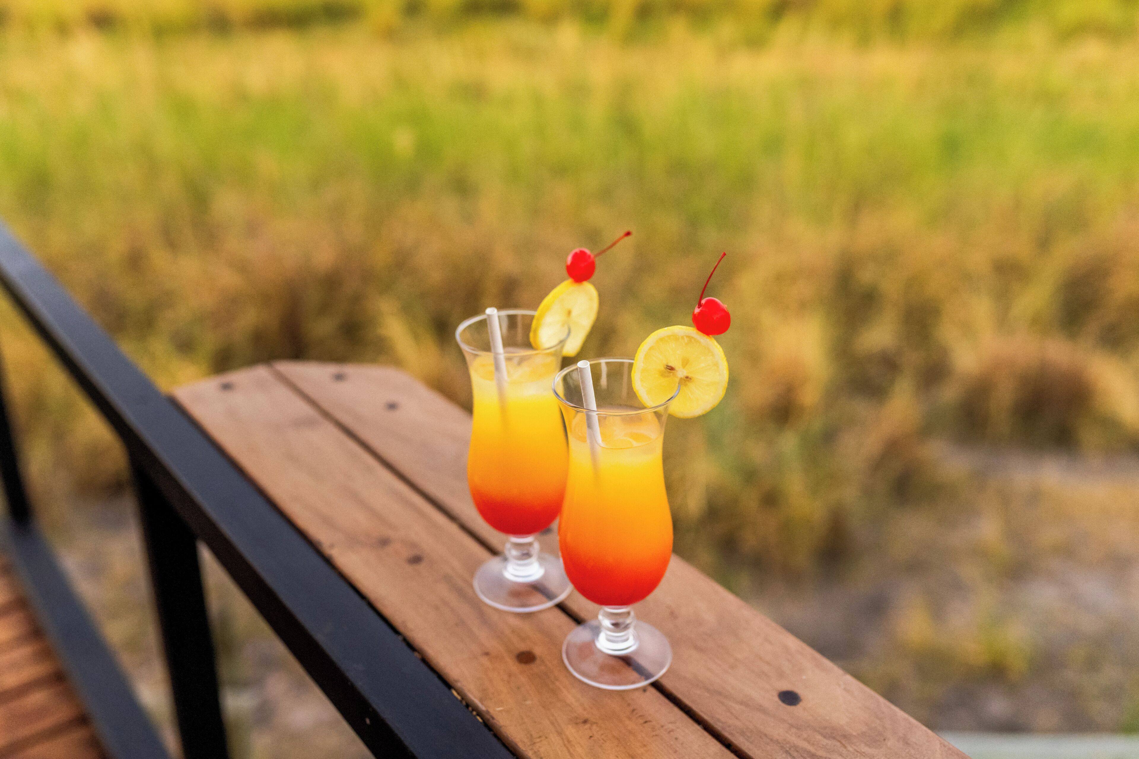 Två glas apelsinjuice med körsbär på ett träbord.