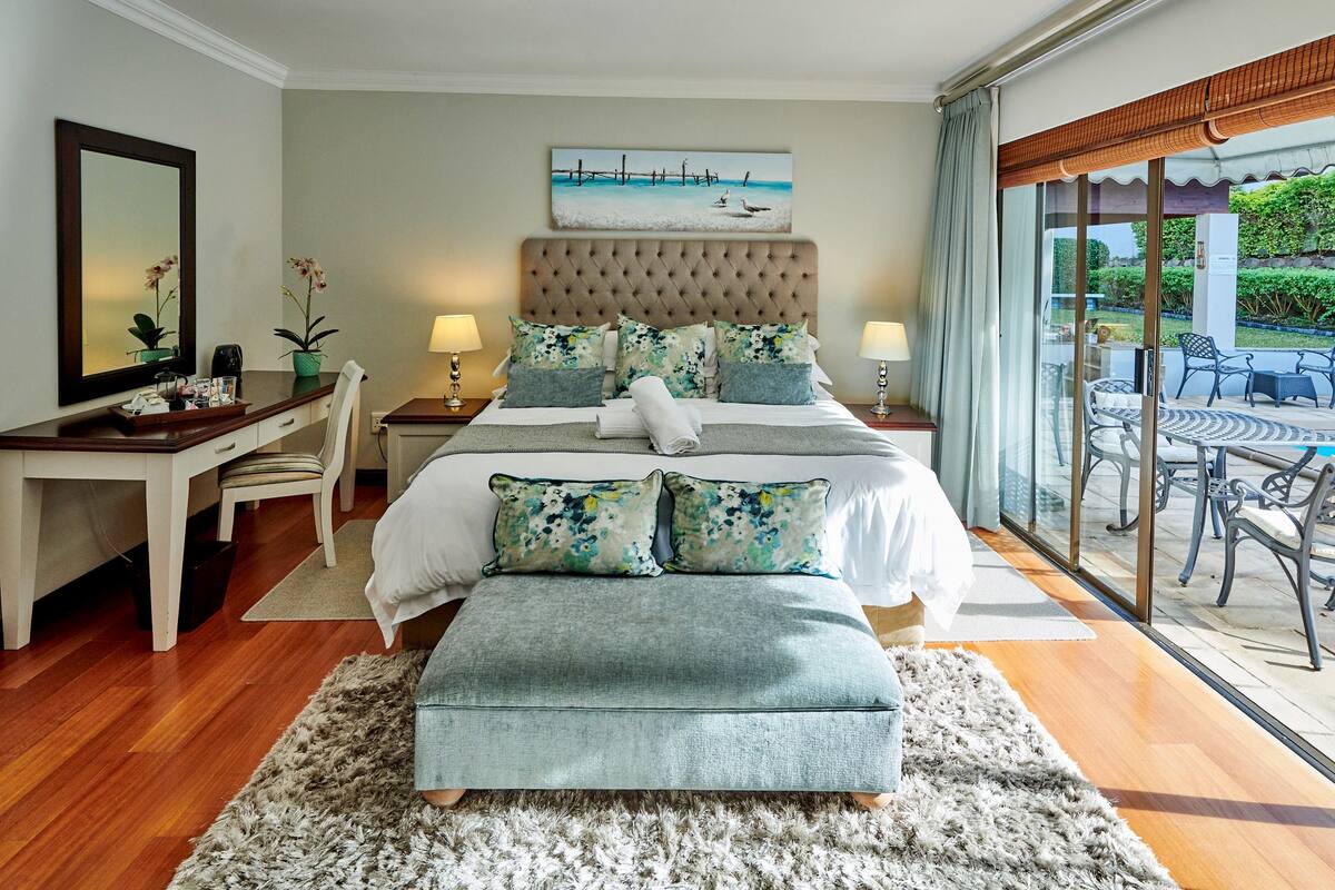 A bedroom with a large bed, a desk, and a view of the outdoors.