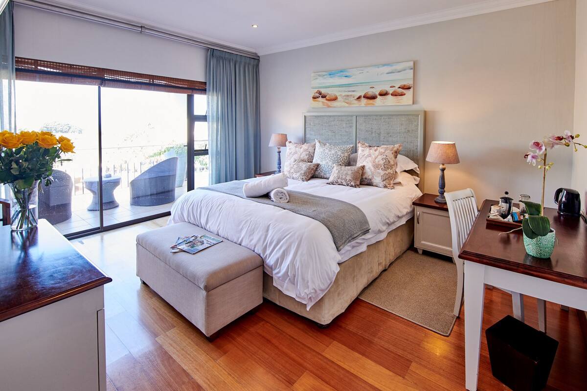 A spacious bedroom with a large bed, a desk, and a view of the outdoors.