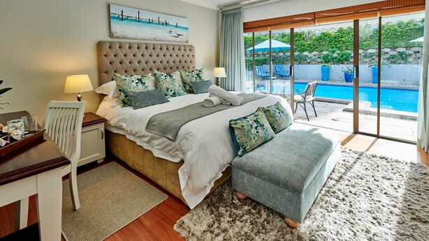 Een slaapkamer met een groot bed, uitzicht op een zwembad en een schuifpui naar een terras.