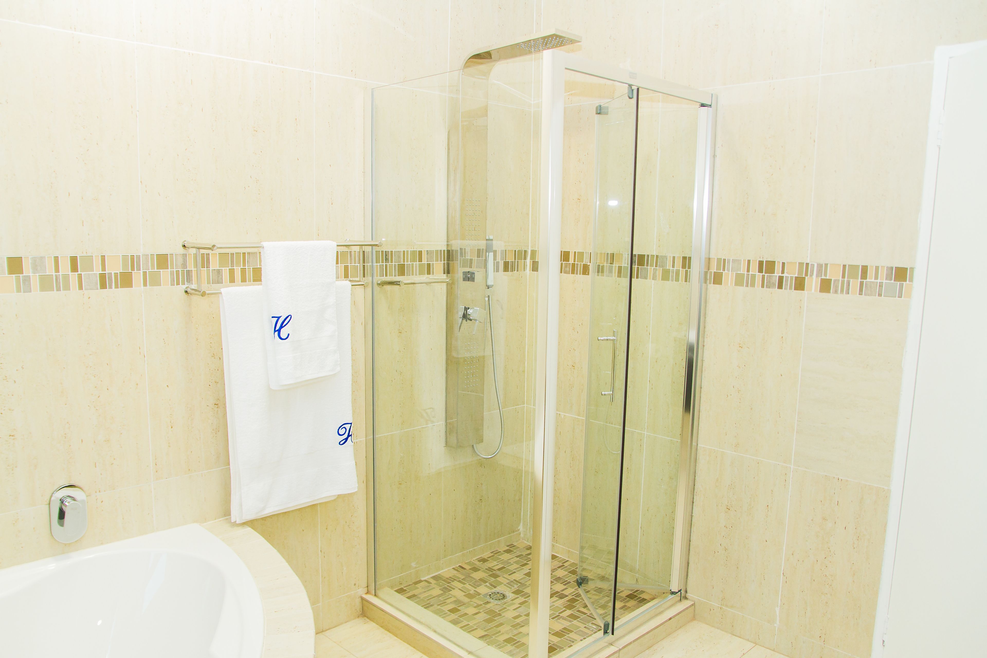 A bathroom with a glass-enclosed shower, a bathtub, and a tiled floor.