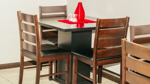 A dining table with four wooden chairs, a red placemat, and a red vase. - Heavenly Boutique Guesthouse (Johannesburg South)