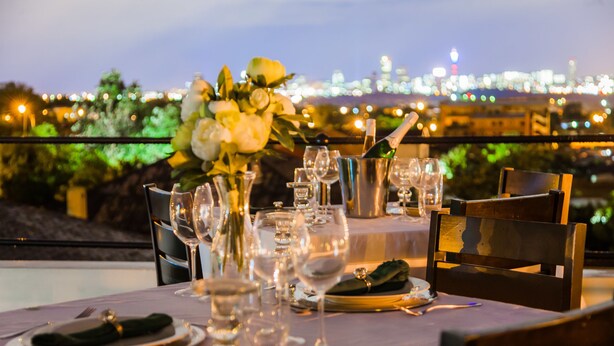 A table set for dining with a city view in the background. - Heavenly Boutique Guesthouse (Johannesburg South)