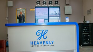 A reception desk with a "Heavenly Boutique Guesthouse" sign, a "No Smoking" sign, clocks displaying different cities, and a framed portrait above the desk. - Heavenly Boutique Guesthouse (Johannesburg South)