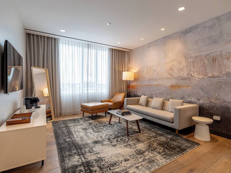 A modern living room with a sofa, armchair, coffee table, and a large abstract painting on the wall.