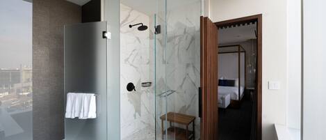 A modern bathroom with a glass-enclosed shower, a white bathtub, and a wooden bench.